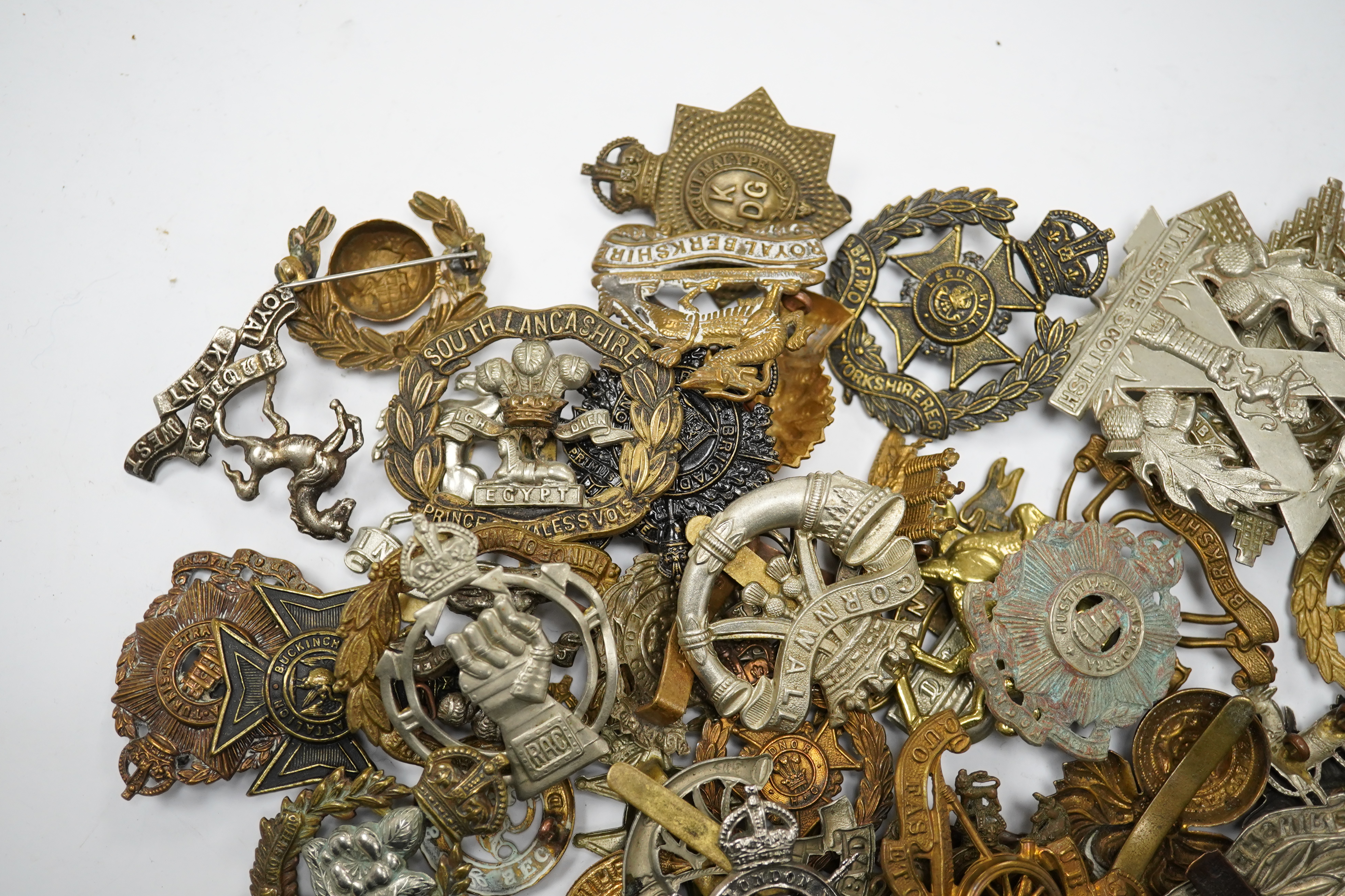 Sixty military cap badges, including; the Hampshire regiment, the South Lancashire Regiment, Prince of Wales Volunteers, the Tyneside Scottish Regiment, the Royal Artillery, the Norfolk Regiment, the Army Ordinance Corps